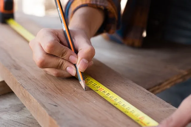 insured hands of a construction using measuring tape and pencil